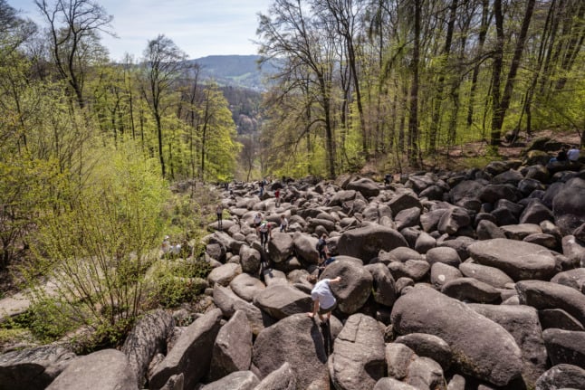 Visitors climb over large rocks in the Odenwald
