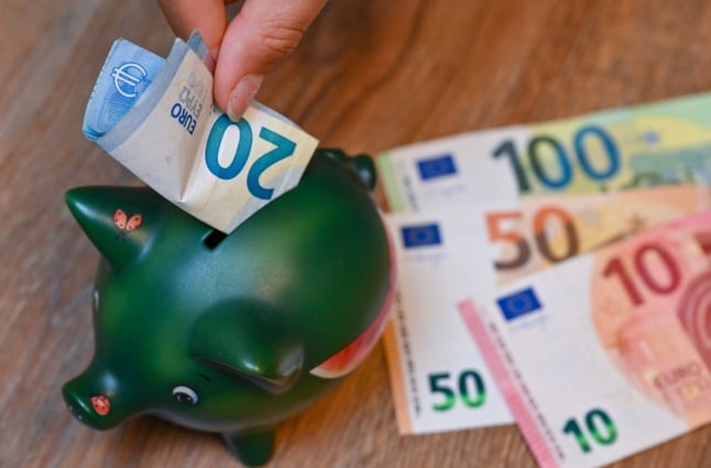A person places money in a piggy bank.