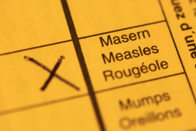A vaccination booklet with a cross at the Measles box.