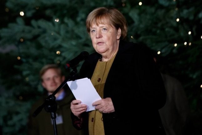Outgoing Chancellor Angela Merkel stands next to a Christmas tree in the chancellor's office.