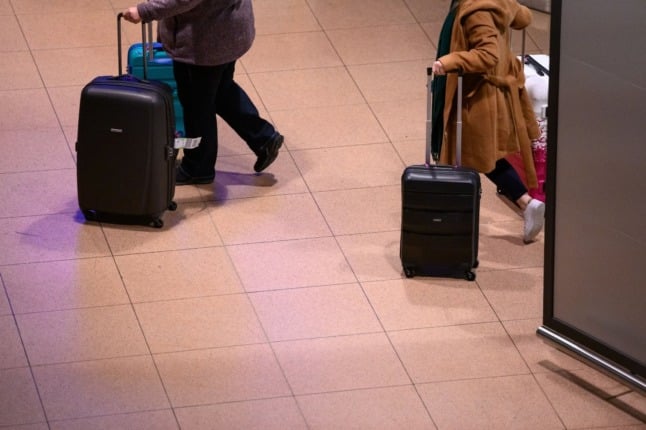 People walk in Hamburg airport with suitcases. 
